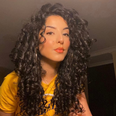 Selfie photo of Fatima Rahouma wearing a  yellow Lakers basketball t-shirt and has long curly black hair.