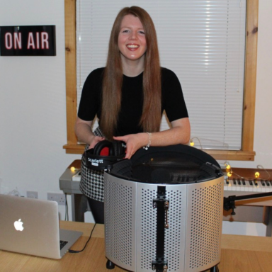 Image of Kara Conway, in a radio studio and smiling to the camera