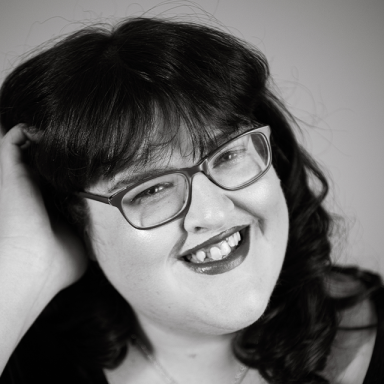 charlotte forman wears glasses, has dark hair with a fringe and smiles
