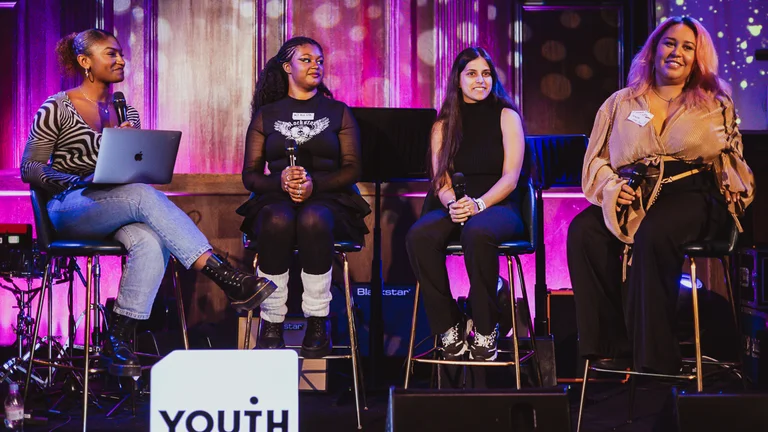 a group of women sit on stage as part of a panel