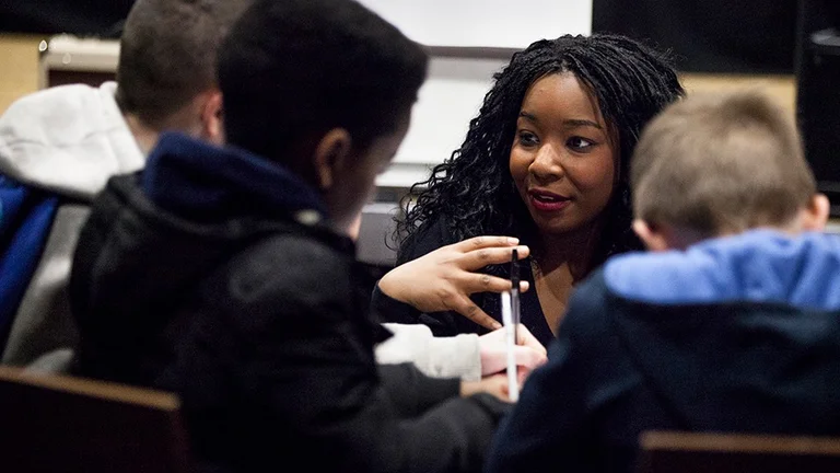 Black Teacher Talking to three of their students in a workshop