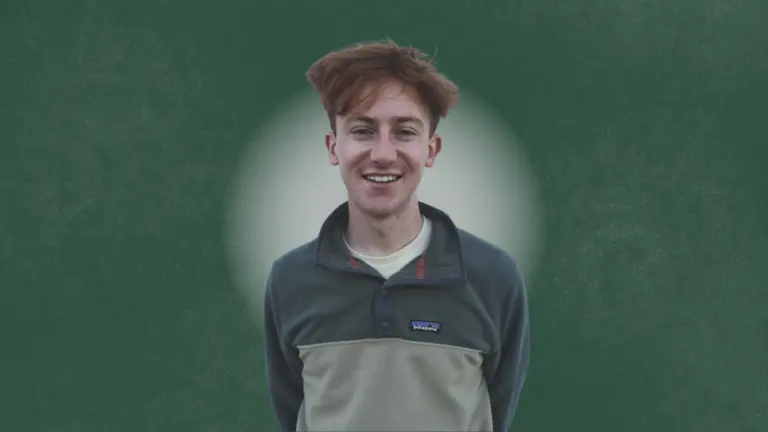This is a photograph of the person interviewed for this article. They are standing looking directly at the camera smiling. The background is green with a white circle behind the person.  