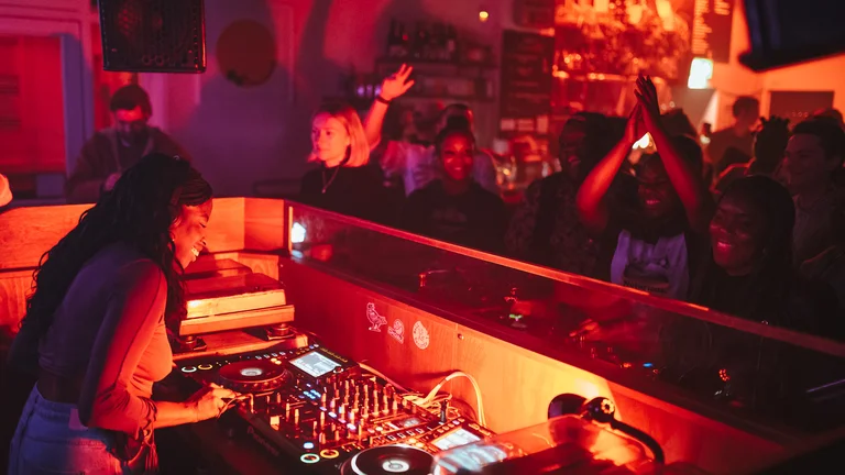 a person DJs in an intimate club setting to a cheering crowd