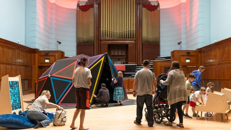 Image of Soundplay's immersive experience, with an organ at the end of a large room, and children playing in their sensory dome.
