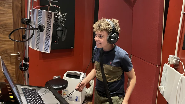 Young boy with headphones on in recording studio smiling