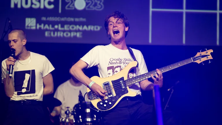 band members perform on stage; a guitarist is in focus