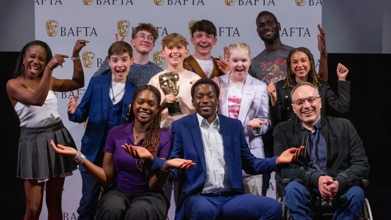 a group of people pose in front of a bafta branded board