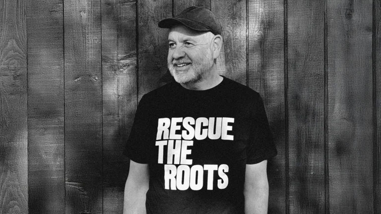 anthony burrill is photographed in black and white wearing a tshirt with the sloagan 'rescue the roots'