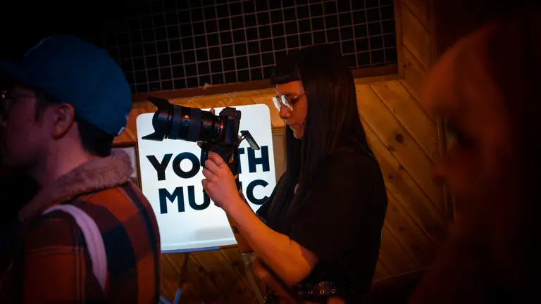 a girl with dark straight hair and glasses holds a professional camera