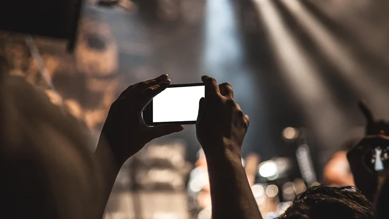 hands holding up a phone to record a concert