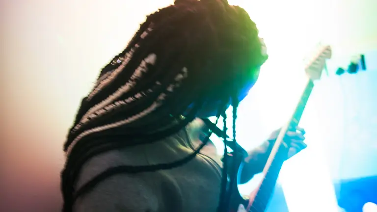 a person with braids plays an electric guitar