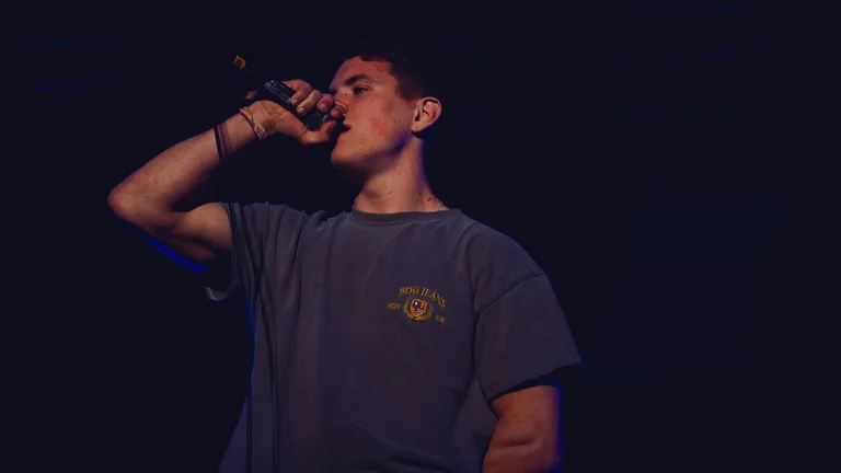 hulton holds a mic and performs on stage