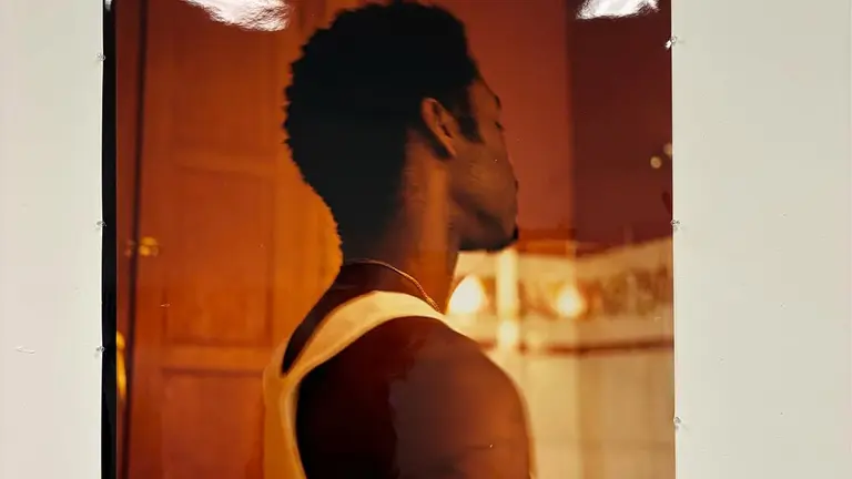 a man is pictured from the side. he is wearing a white tank top
