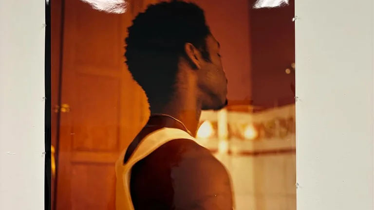 a man is pictured from the side. he is wearing a white tank top