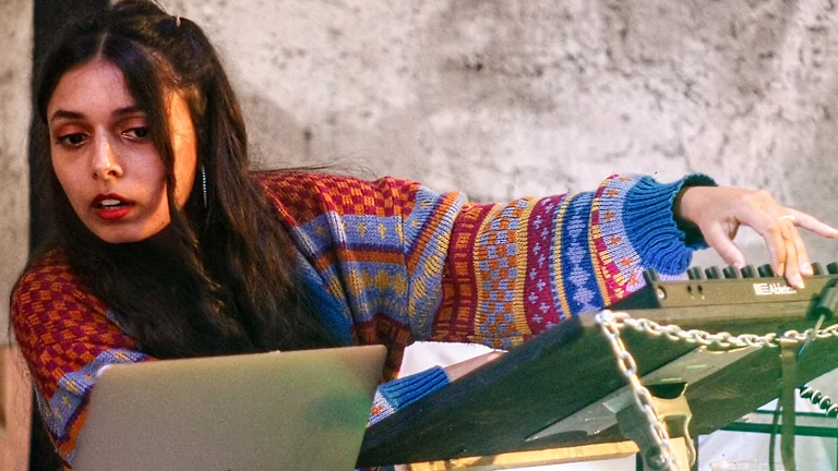 a woman with dark hair in pigtails uses music production equipment