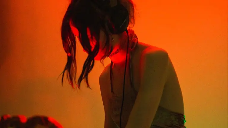 a person DJs, their face obscured by two strands of hair