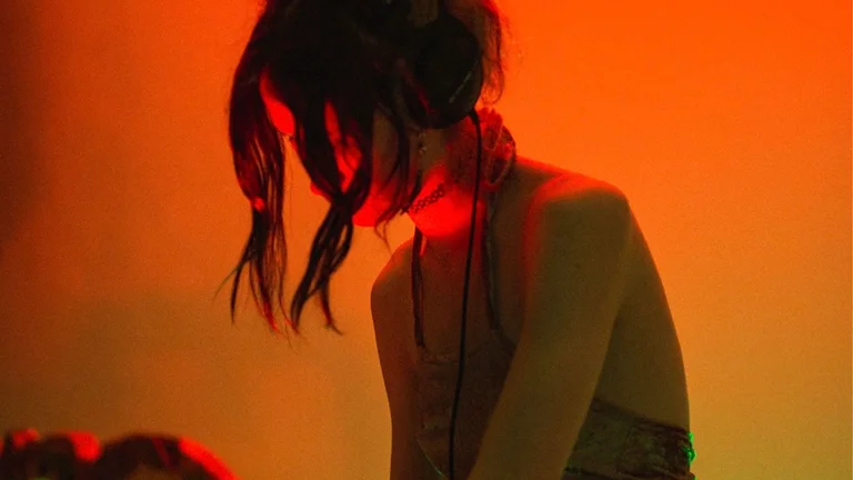 a person DJs, their face obscured by two strands of hair