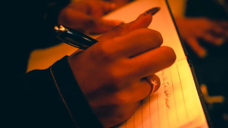hands use a pen to write in a notebook
