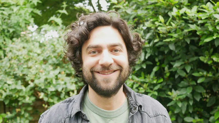 Man smiling to camera with vegetation in the background