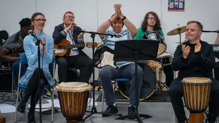 Five young people playing using music with instruments and clapping