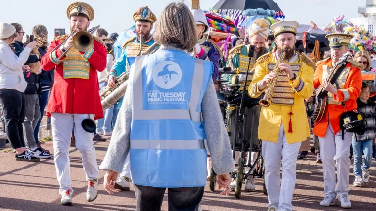 A street band playing behind a Hastings Fat Tuesday steward 