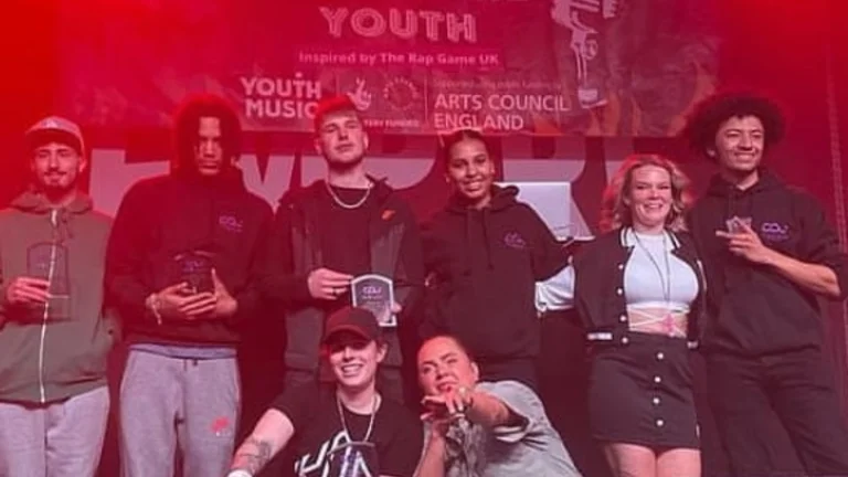 eight young people in a stage with red light and a banner behind