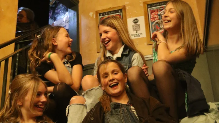 Five girls laughing together while sitting in stairs