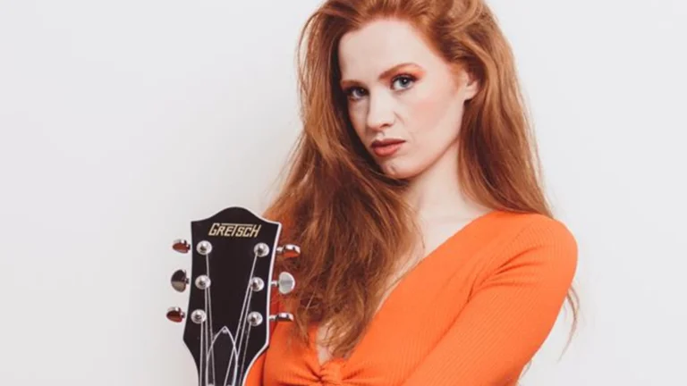 Image of Stephanie Cheape, orange shirt holding a guitar