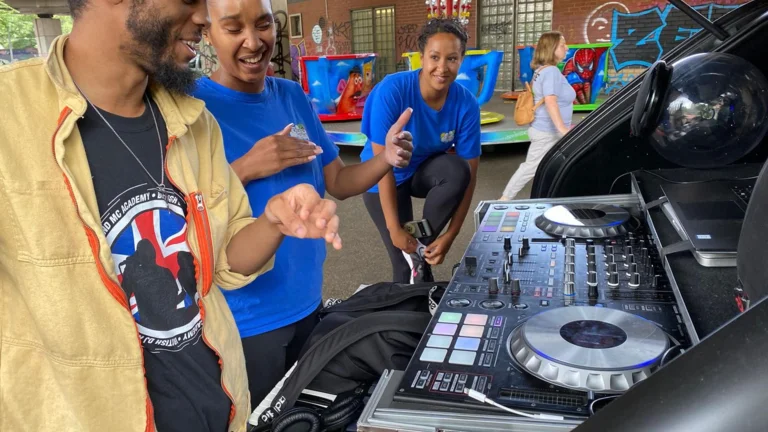 three people in a DJ booth and laughing