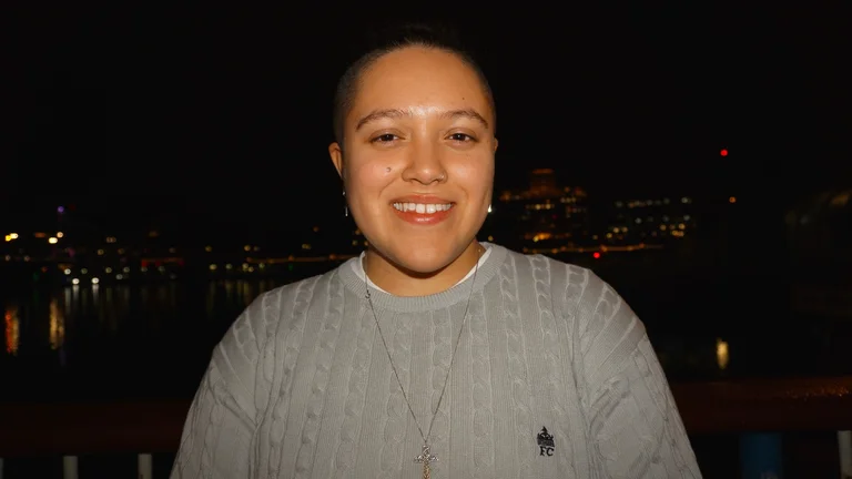 Lauren at night smiling at the camera in a grey jumper