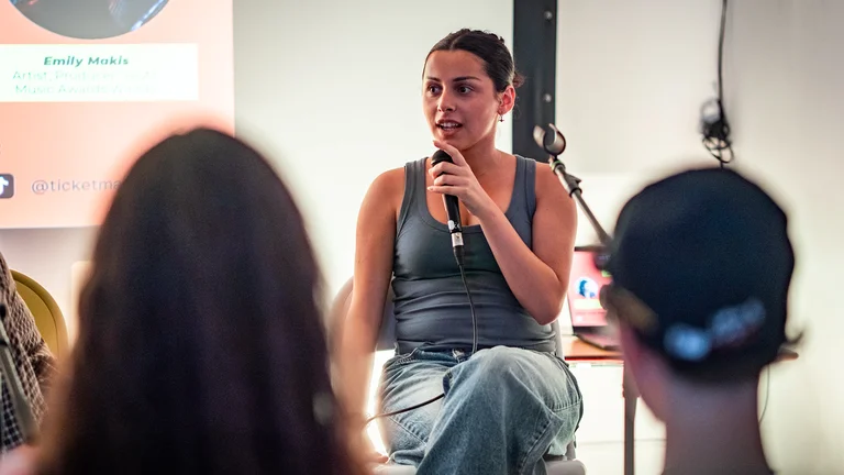 emily makis holds a microphone on a panel