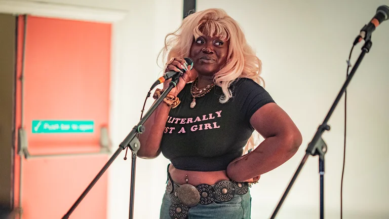 a woman with blonde hair and a black crop top holds a mic
