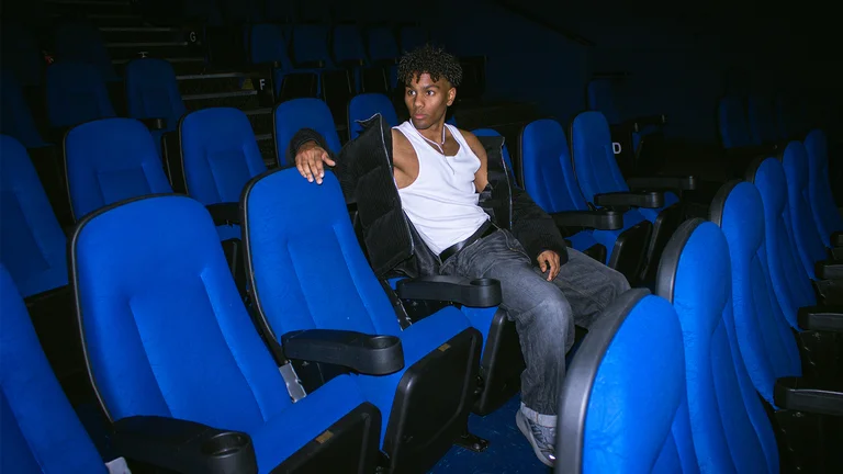 exojay reclines on a blue seat in a dark cinema