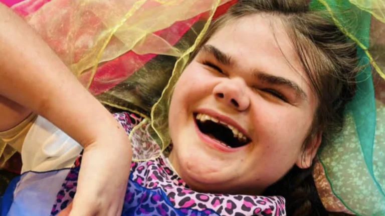 Smiling young child over a bed of fabric and with an animal print scarf