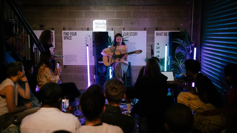 a musician holds a guitar and performs to a crowd