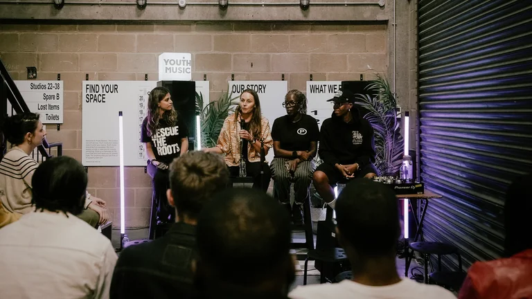 a panel of people sit on chairs in front of an audience