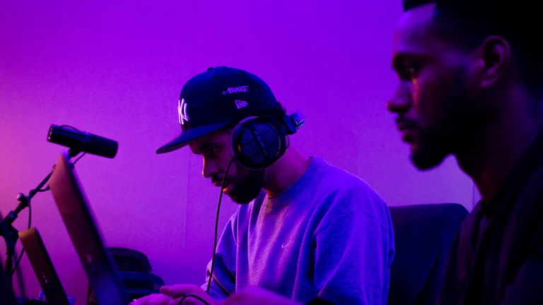 Purple light, two men working on laptops, making music