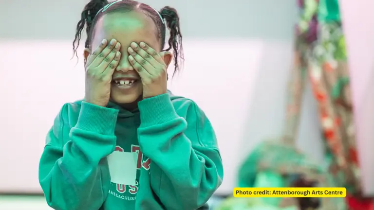 A child with their hands covering their eyes, as if they are playing hide and seek.