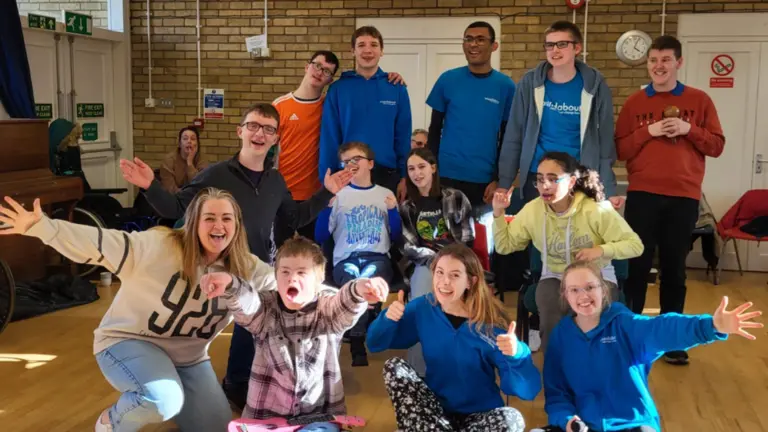 Rebecca Tunley posing for a photo in a hall with all her participants, arms out and cheering