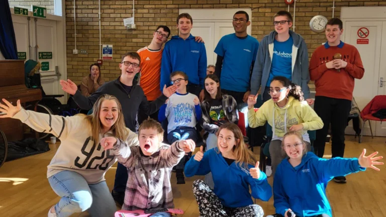 Rebecca Tunley posing for a photo in a hall with all her participants, arms out and cheering