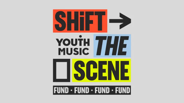 A grey square with Shift The Scene Fund written on it. The words are highlighted in red, blue and yellow. 