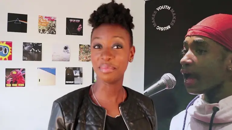 YolanDa in the foreground with a young person singing in the background