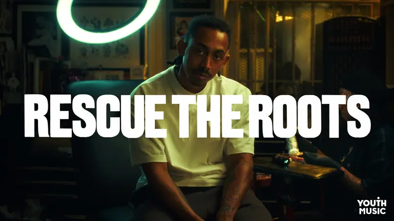 Jordan Stephens posing after getting his tattoo, with "rescue the roots' in bold font imposed on the image