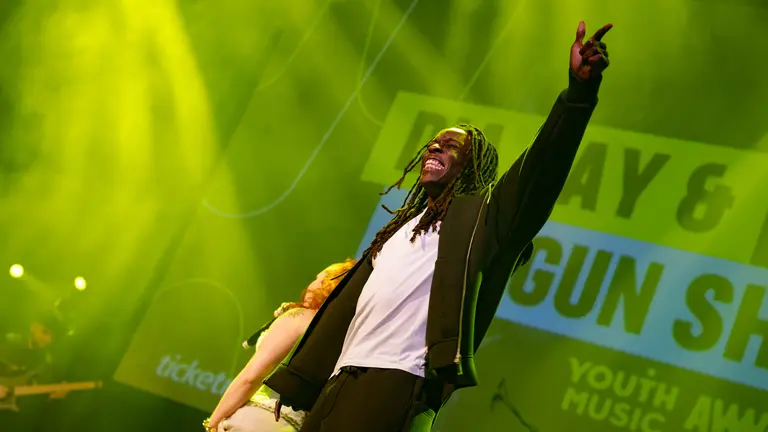 Shogun Shato on stage at the Youth Music Awards 2025, one arm in the air and smiling to the crowd