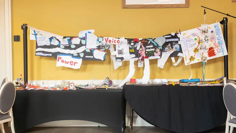 a collage created by the energiser fund participants. lots of handmade posters are lined up next to each on a table in front of a yellow wall