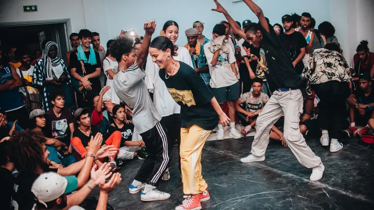 Big group of young people, some dancing and others sitting and watching the performance