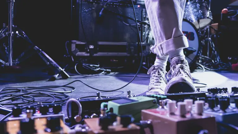 a person in a stage wearing white trousers and white all stars sneakers. 