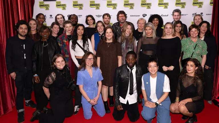 The Youth Music Staff posing for a photo at the Youth Music Awards. Youth Music branding behind them, on a red carpet.
