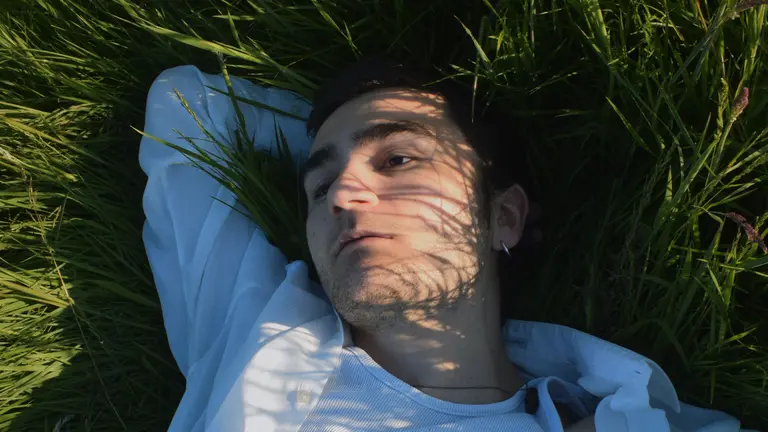 arakel lies down on the grass with one arm above his head