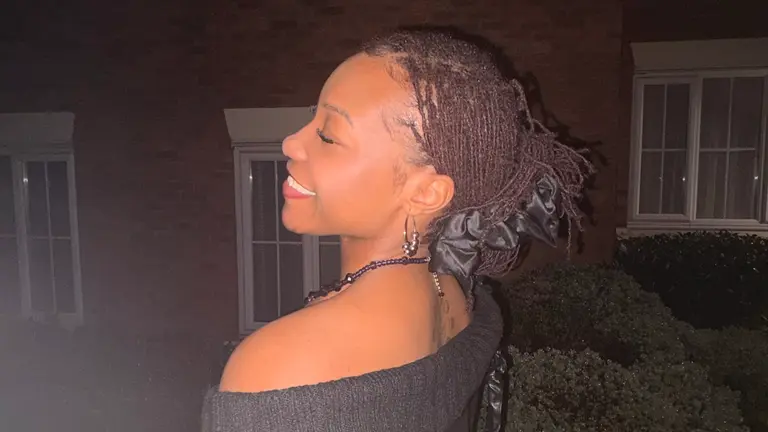 a woman with braids in a bun smiles